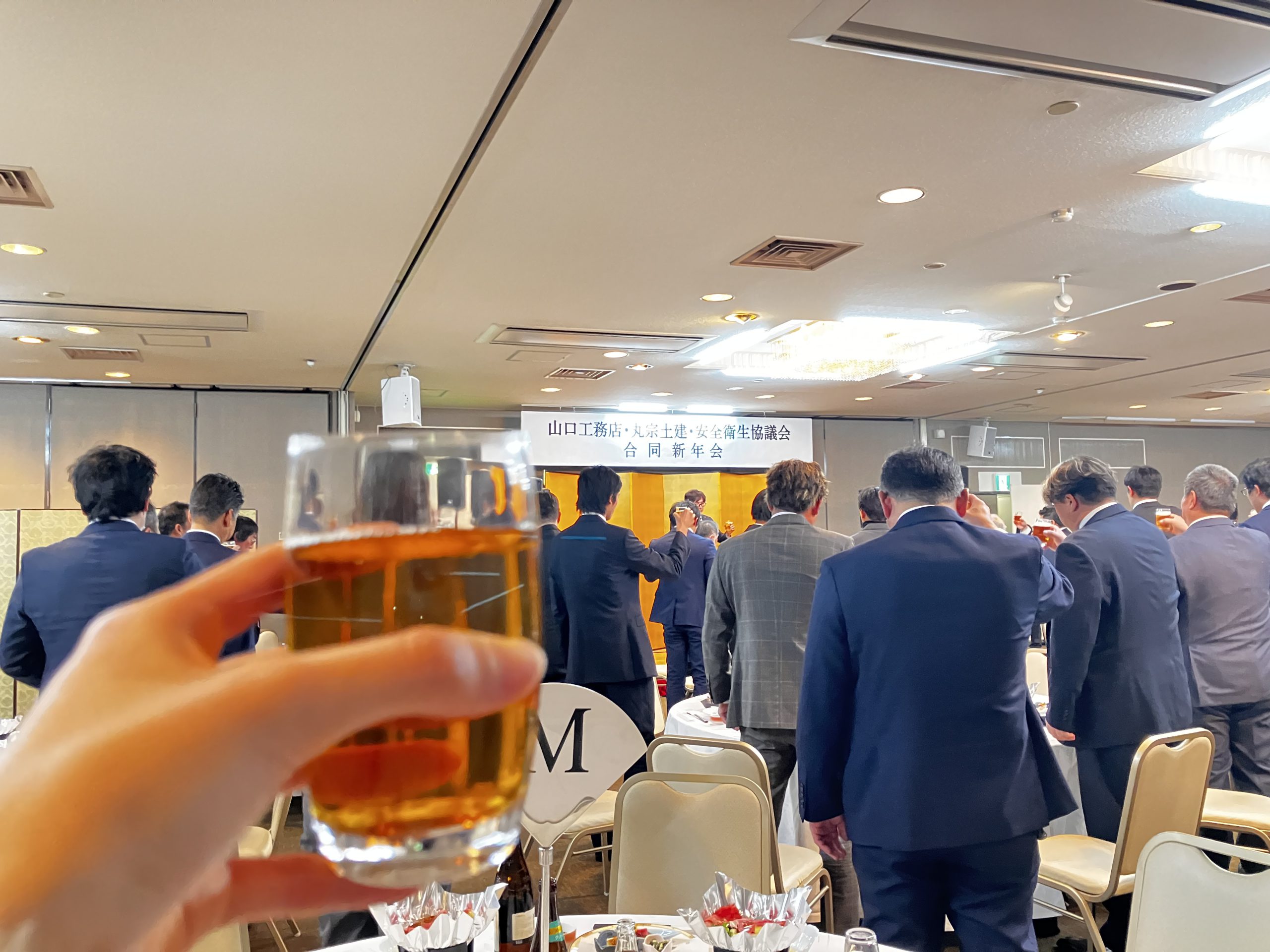 新年会での乾杯の瞬間にグラスを掲げる写真